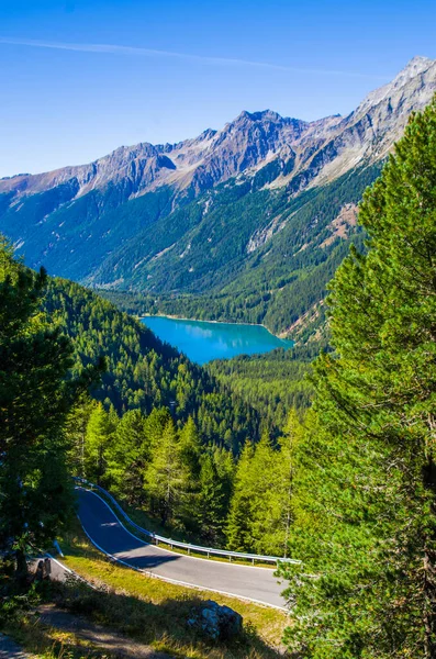 蓝天下明亮的蓝山湖 环绕着翠绿的树林 花岗岩石和雪的顶部 — 图库照片