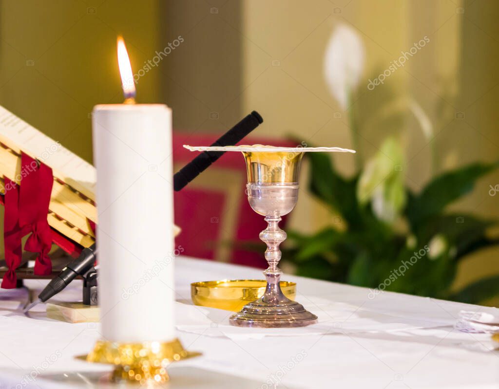 in the church the lit candle illuminates the wine, blood of christ, and the host, the body of christ for the communion of the faithful