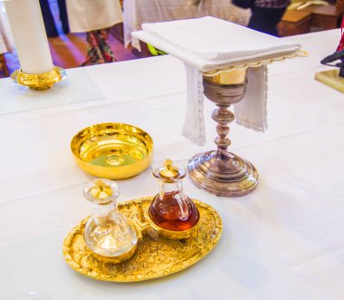 chalice for wine, blood of christ, and ciborium with host, body of christ, and ampoules with wine and water for the consecration on the others of the churches for pope francesco clipart