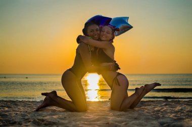 İki kız arkadaşım kumsalda sarılıyorlar