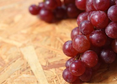 Tahta bir masada taze olgun kırmızı üzümler.