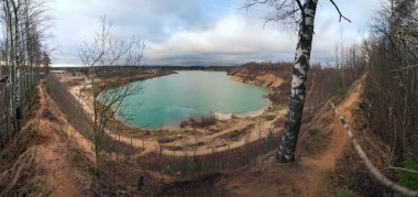 Tepenin tepesinde kum ocağının kıyısındaki ağaçların arasında bir patika var. Panorama..