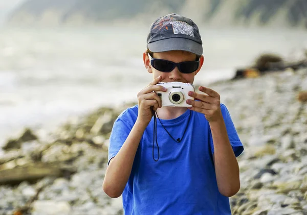Un chico con una cámara dispara al mar en el verano . — Foto de Stock