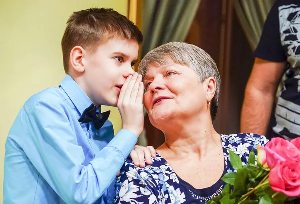Το αγόρι ψιθυρίζει στο αυτί της γιαγιάς του και μοιράζεται τα νέα. . — Φωτογραφία Αρχείου