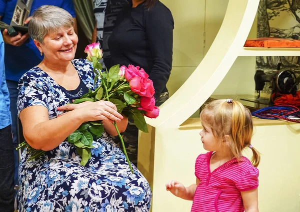 Kız büyükannesini tebrik eder ve çiçek verir. . — Stok fotoğraf