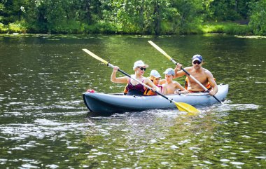 Oğlu ve kızı olan genç bir aile gölde kayak yapıyor. .