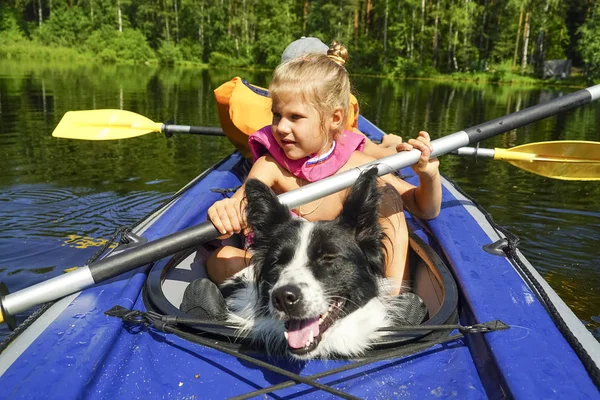 A girl with a dog sitting in a kayak on the lake. — Stock Photo, Image