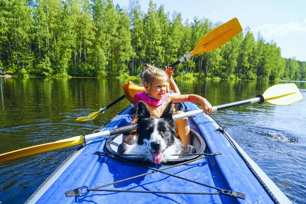 A girl with a dog sitting in a kayak on the lake . — Stock Photo, Image