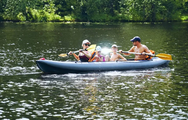 A young family with a son and daughter are kayaking on the lake . — Stock Photo, Image