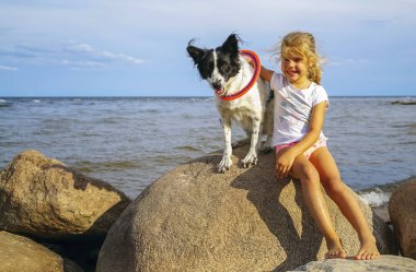 7 yaşında bir kız sahilde köpeğine sarılıyor. .