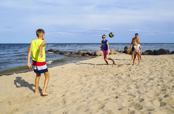 A family with a son and daughter playing with a ball on the beach. — Stock Photo, Image
