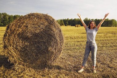 Çavdar tarlasında bir saman yığınının yanında duran genç bir kız