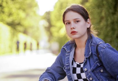 Yeşil bir sokakta, parkta genç bir kız..