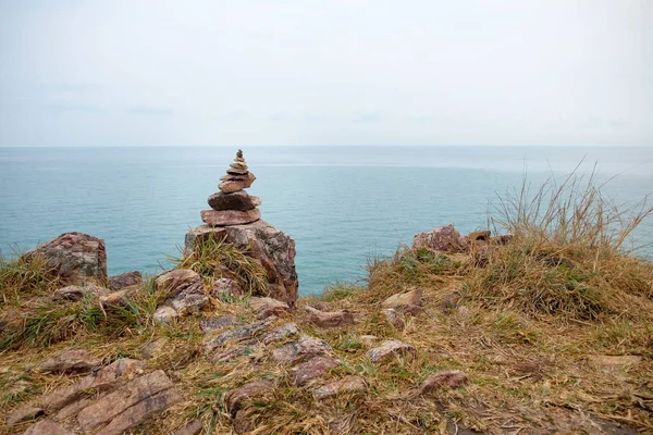 Cliffside deniz manzarası arka plan ile denge taş yığını 