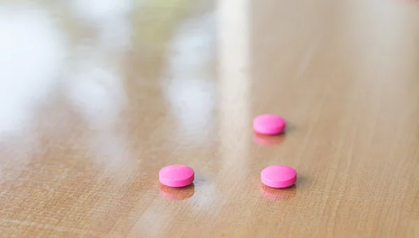Pillole rosa sulla sfocatura teble . — Foto Stock