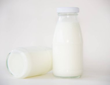 Beyaz arka planda bir şişe süt.