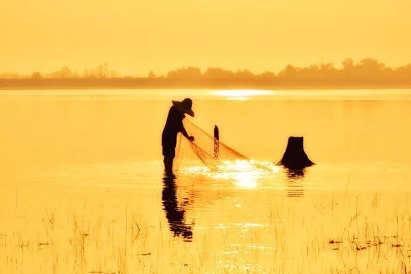 Fishing man in silhouette on gold sunset background. — Stock Photo, Image