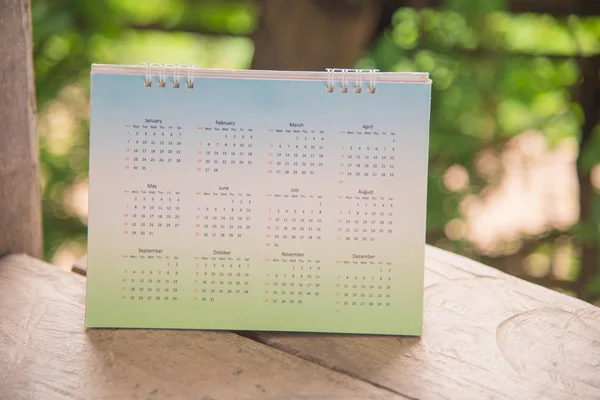 Calendário branco no fundo borrão verde . — Fotografia de Stock