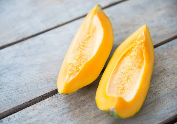 Ahşap masa üzerinde sarı papaya meyve.