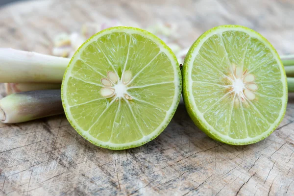 Ahşap kesme tahtası üzerinde yeşil limon. — Stok fotoğraf