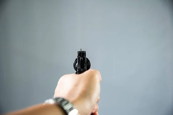 Pistol i handen på grå bakgrund. — Stockfoto