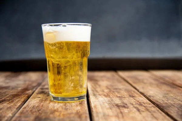 Cerveza en vidrio sobre mesa de madera. — Foto de Stock