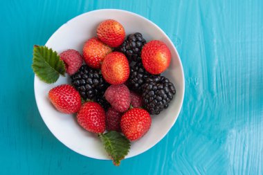 Mavi arka planda beyaz böğürtlen kasesini kapat.