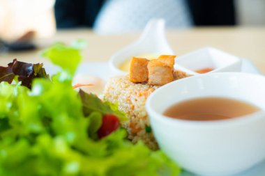 Beyaz tabakta yeşil marullu kızarmış pirinç somonu..