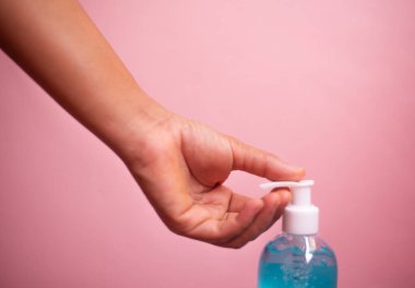 Kapalı el ele tutuş alkol jeli şişesi korunmuş corona veya pembe pastel arka planda Covid-19 virüsü.