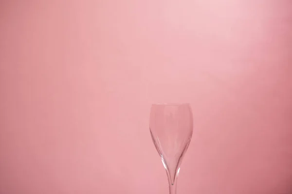Blank wine glass on pink pastel background.