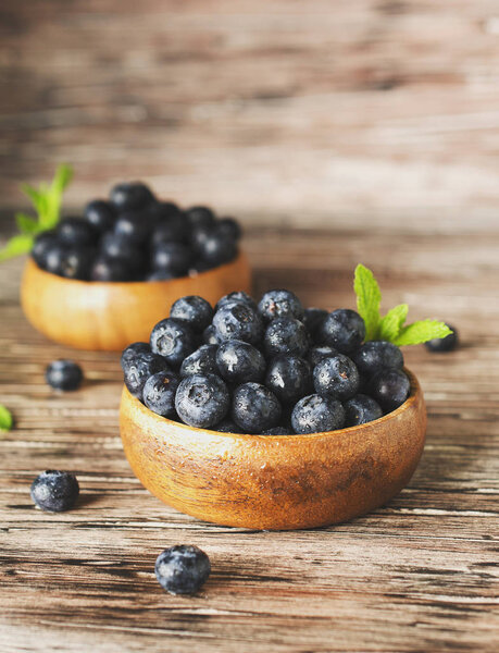 fresh bilberries or blueberries in small wooden bowls, selective focus