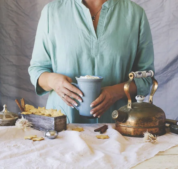 Handen van de vrouw met een kopje cacao boven de eettafel, selectieve aandacht — Stockfoto