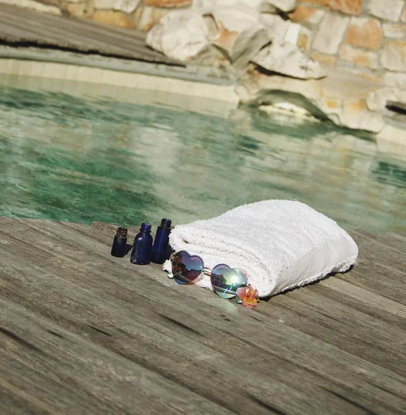 White towel and sunglasses the form of heart on the edge of a blue swimming pool, selective focus — Stock Photo, Image