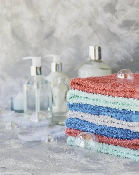 Stapel handdoeken voor de badkamer flessen op een witte marmeren achtergrond, ruimte voor tekst, selectieve aandacht — Stockfoto