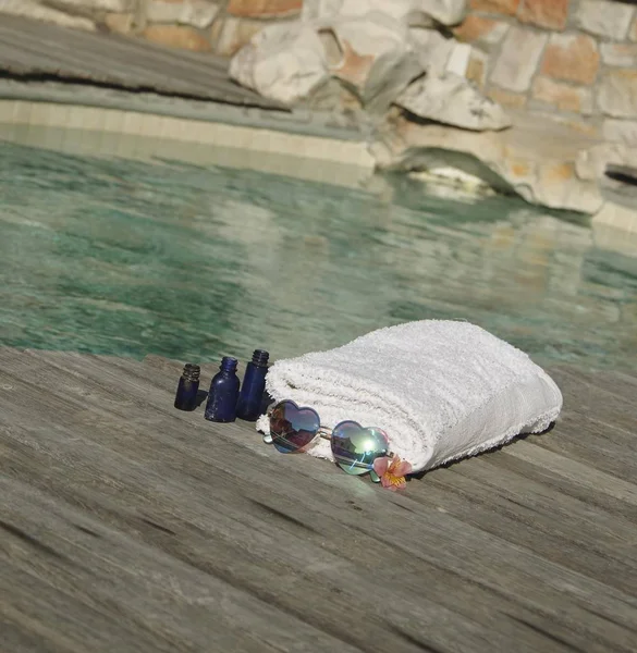 White towel and sunglasses the form of heart on the edge of a blue swimming pool, selective focus — Stock Photo, Image