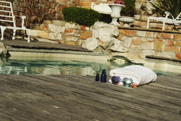 White towel and sunglasses the form of heart on the edge of a blue swimming pool, selective focus — Stock Photo, Image