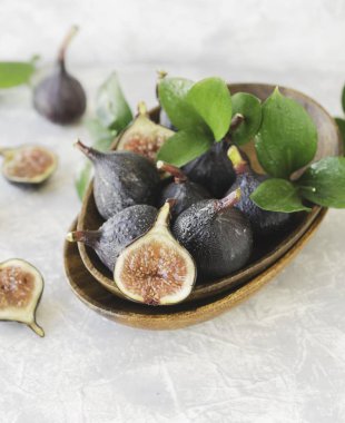 bir masada beyaz mermer, seçici odak ahşap bir kasede koyu mavi taze incir