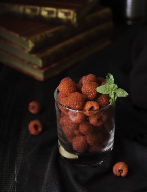 Olgun Ahududu ve kitaplar, seçici odak, kavram arka plan üzerine nane ile cam