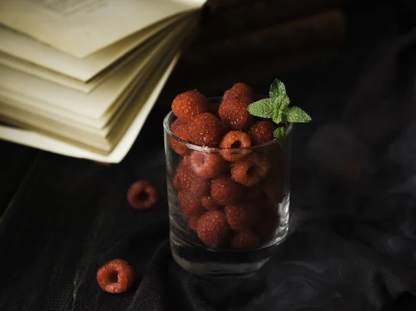 Vidrio con frambuesas maduras y menta en el fondo de los libros, enfoque selectivo, concepto — Foto de Stock