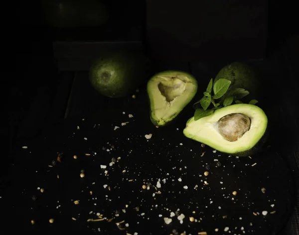 Avocado en specerijen op zwarte houten tafel met fruit, selectieve aandacht, begrip — Stockfoto