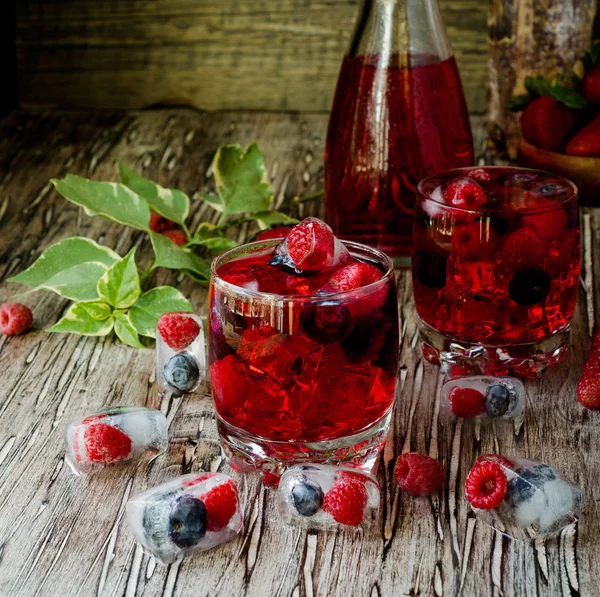 Limonata di bacche estive con frutti di bosco congelati su un tavolo rustico in legno, messa a fuoco selettiva — Foto Stock