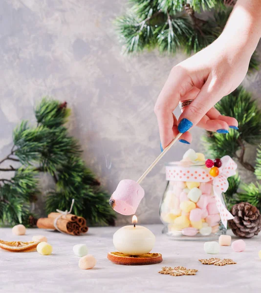 Pane tostato un marshmallow sopra una candela durante Natale e Anno nuovo su un tavolo bianco di legno, messa a fuoco selettiva — Foto Stock