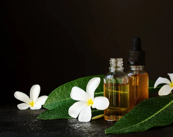 silhat çiçekler spa tedavileri siyah arka plan, seçici odak için petrol ve Frangipani Plumeria ile küçük cam kavanozlar
