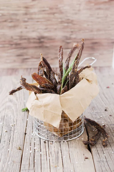 Prudce maso, kráva, jeleni, divoké zvíře nebo biltong v kraft papír misky na rustikální stůl, Selektivní ostření — Stock fotografie