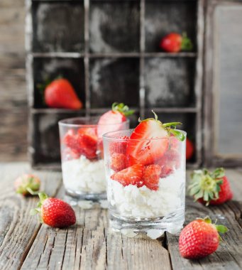 Kırmızı olgun çilek süzme peynir veya yoğurt ile seçici odak bir rustik masaya Servis Kahvaltı