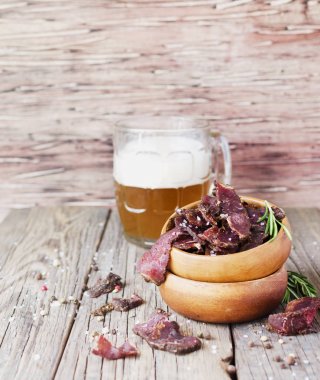 jerked meat, cow, deer, wild beast or biltong in wooden bowls on a rustic table, selective focus clipart