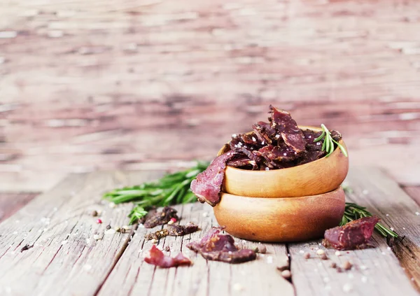 Jerked meat, cow, deer, wild beast or biltong in wooden bowls on a rustic table, selective focus — Stock Photo, Image