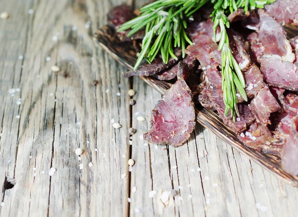 Jerked meat, cow, deer, wild beast or biltong in wooden bowls on a rustic table, selective focus — Stock Photo, Image