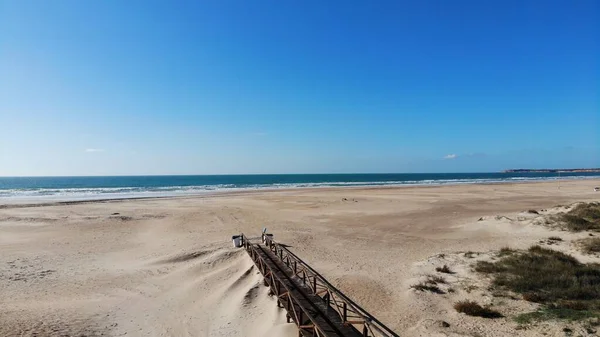 Eski kasabadan kumlu okyanus sahiline tahta patika