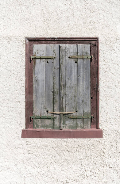 Old window with closed shutter, tied up with a rope